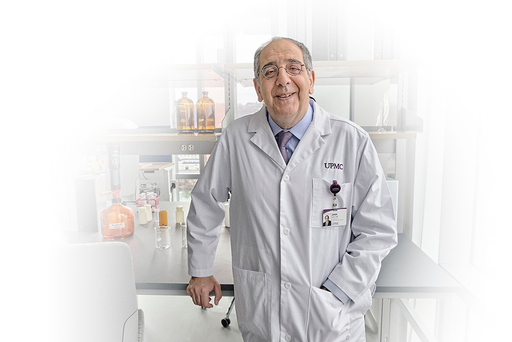 Dr. Jose-Alain Sahel dressed in a labcoat stands in front of laboratory equipment.